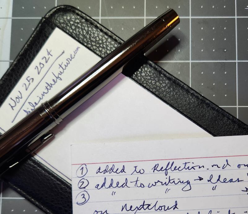 A card with some brief notes lays next to a pen on top of a leather card wallet.